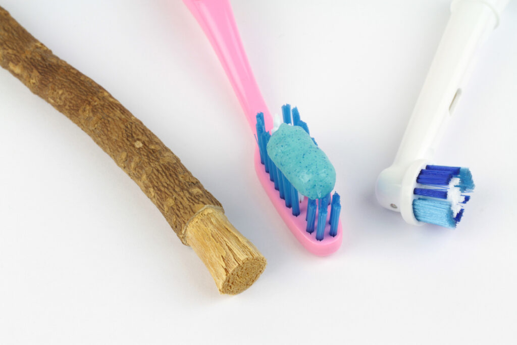 Miswak twig, traditional toothbrush, and electric toothbrush on white background